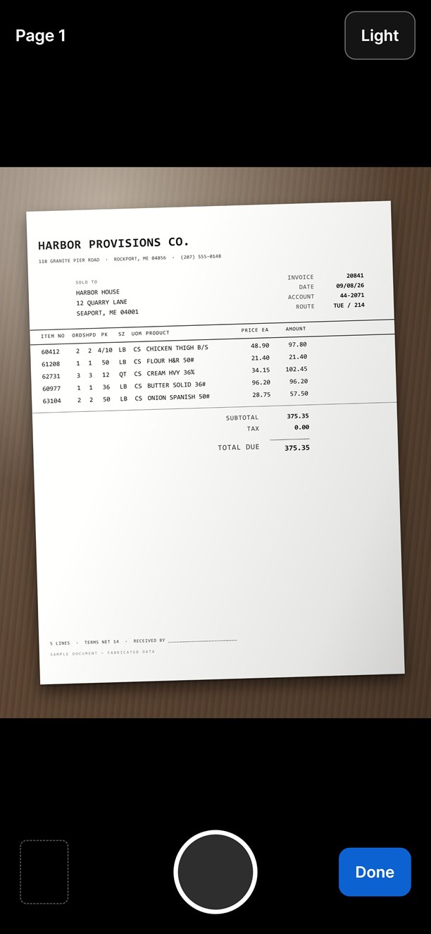 The phone's camera frame over an invoice lying flat on a desk, shutter ready.